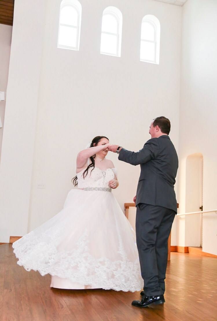 The groom twirls the bride in her blush wedding dress during their first dance at Darlington Chapel in El Reno, Oklahoma 